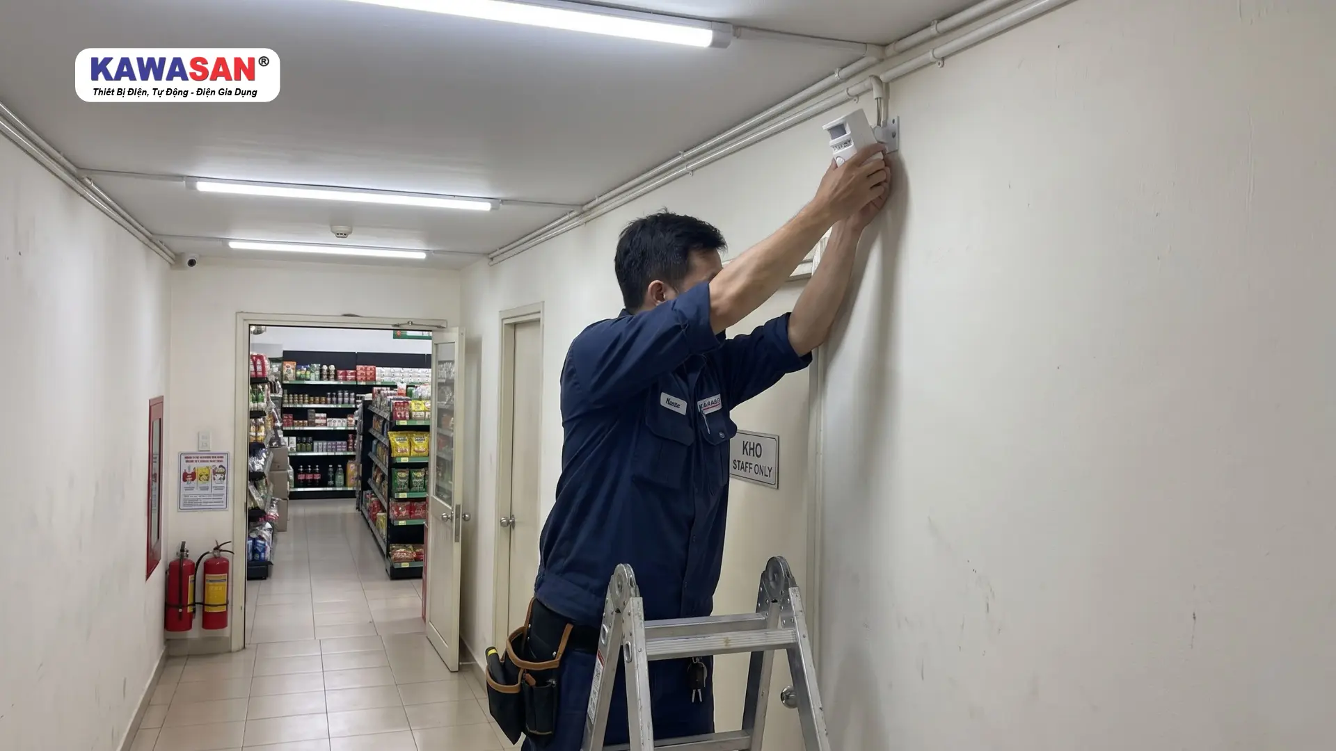 Kỹ thuật viên lắp cảm biến báo trộm trên tường hành lang cửa hàng