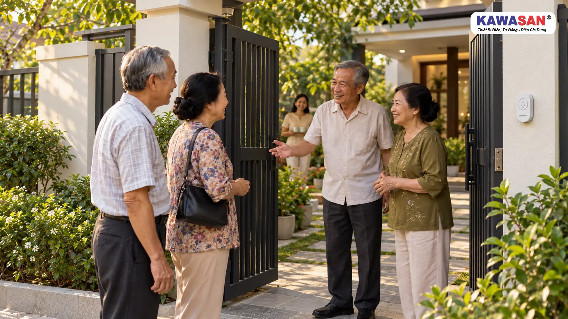 Bố mẹ lớn tuổi chào đón đôi bạn tại cổng mở, nút chuông KAWASAN gắn trên trụ cổng bên phải.