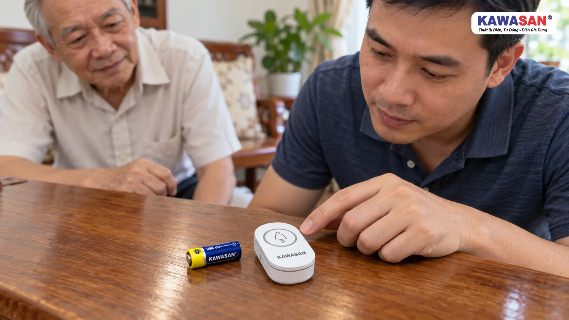 Con trai kiểm tra nút nhấn chuông cửa KAWASAN trên bàn gỗ, cạnh viên pin 23A 12V, người bố quan sát.